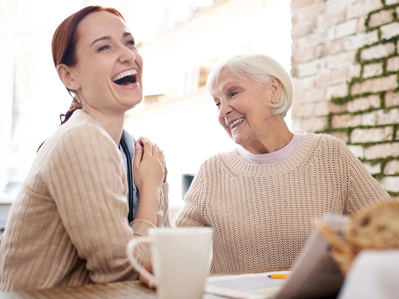smiling woman helping elderly